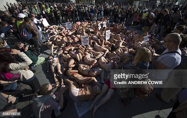 Onlookers crowd around 100 people lying naked or partially clothed on the floor in Trafalgar Square covered in fake blood as part of a PETA protest...