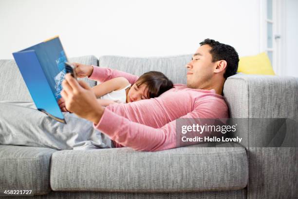 father and daughter reading together on sofa - blick nach unten stock-fotos und bilder