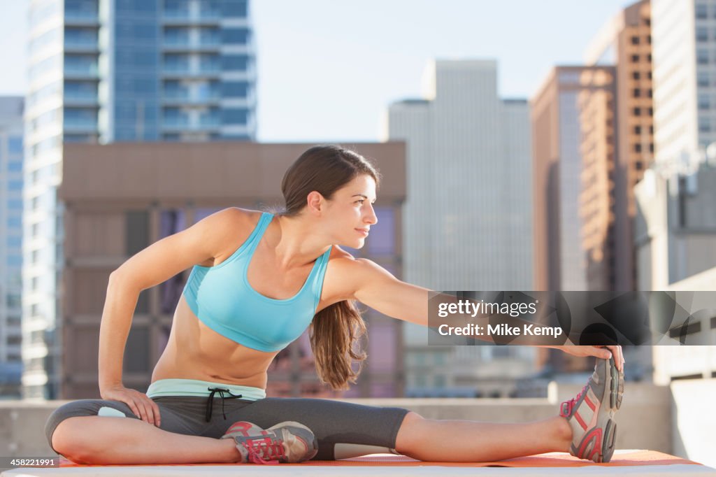 Caucasian woman stretching on urban rooftop