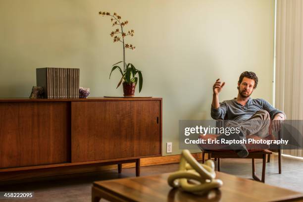 caucasian man relaxing in living room - man living room stockfoto's en -beelden