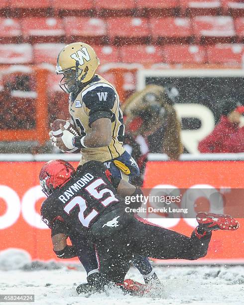 Keon Raymond of the Calgary Stampeders tries to tackle Cory Watson of the Winnipeg Blue Bombers during a CFL game at McMahon Stadium on November 1,...
