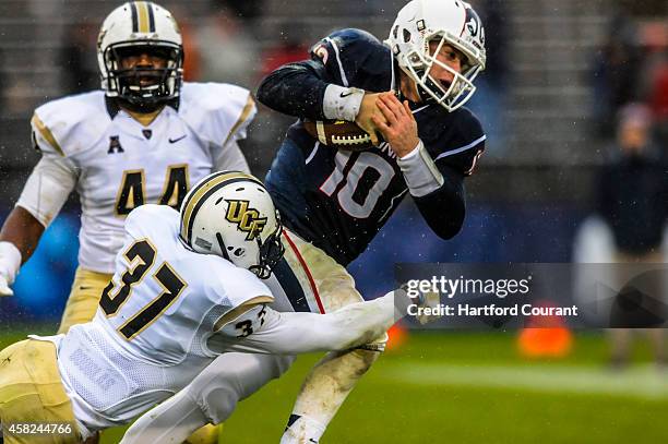 Connecicut quarterback Chandler Whitmer is brought down by Central Florida's Miles Pace and Brandon Alexander during the second half at Rentschler...