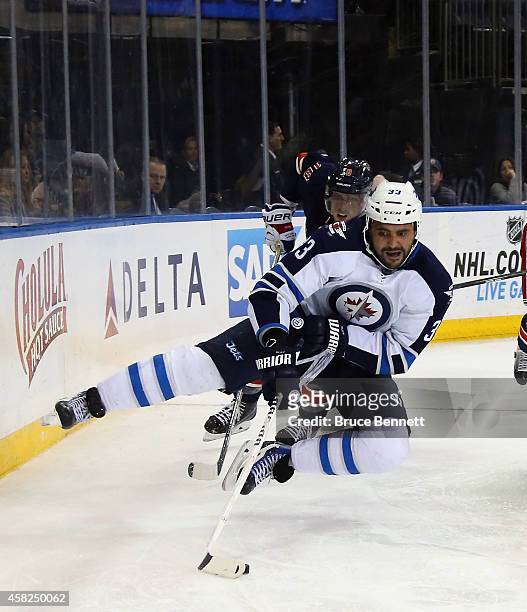 Dustin Byfuglien of the Winnipeg Jets is tripped up by Marc Staal of the New York Rangers during the third period at Madison Square Garden on...