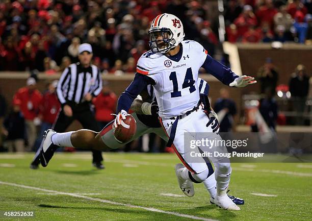 Quarterback Nick Marshall of the Auburn Tigers eludes Robert Nkemdiche of the Mississippi Rebels and completes a first down pass in the third quarter...