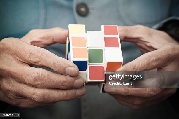 hände spielt eine würfelspiel - rubiks cube stock-fotos und bilder