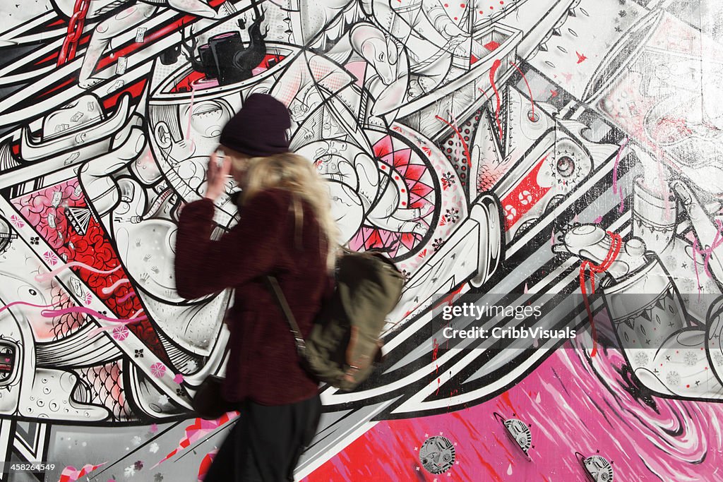 NYC jovem caminhando passado como Nosm arte de rua mural
