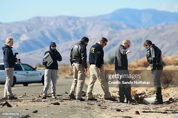 Agents from the National Transportation Safety Board , FBI and Sheriff's comb through the wreckage of the Virgin Galactic SpaceShip 2 in a desert...