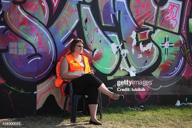 woman sitting by a huge graffiti on roskilde festival - roskildefjorden stockfoto's en -beelden