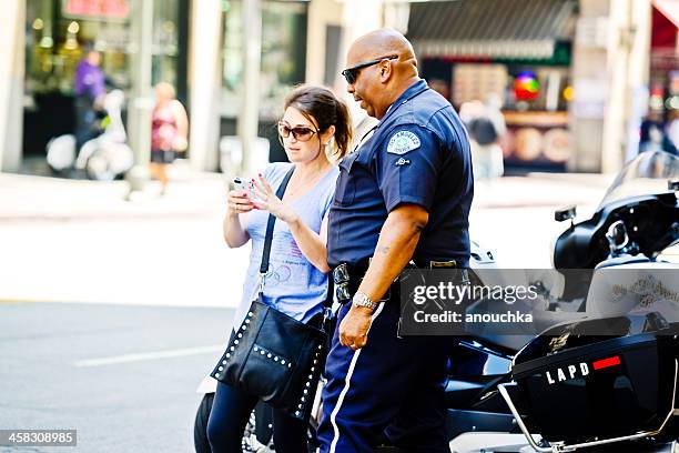 policeman helping woman on los angeles street - brand advocacy stock pictures, royalty-free photos & images