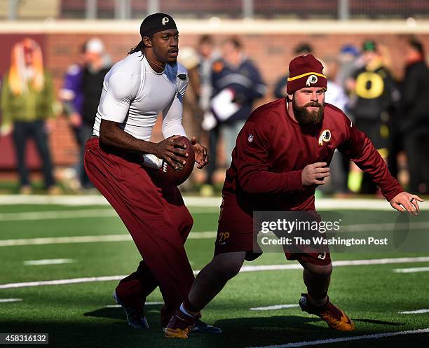 Washington Redskins quarterback Robert Griffin III drops back after taking a snap from Washington Redskins center Kory Lichtensteiger while warming...