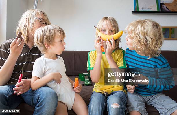 Four brothers at age of three, six, eight and twelve sitting on a couch and eating fruits and vegetables on August 05 in Sankt Augustin, Germany....