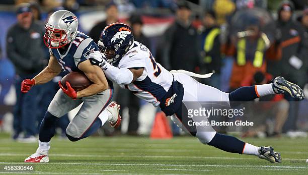Broncos line backer Corey Nelson tries to hang onto Patriots WR Julian Edelman as he picks up some yardage after a catch in the third quarter. The...
