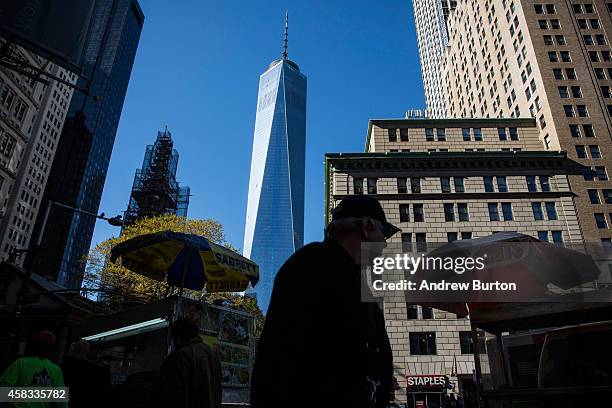 People walk past One World Trade Center, which opens today, on November 3, 2014 in New York City. The skyscraper is 104 stories tall and cost $3.9...