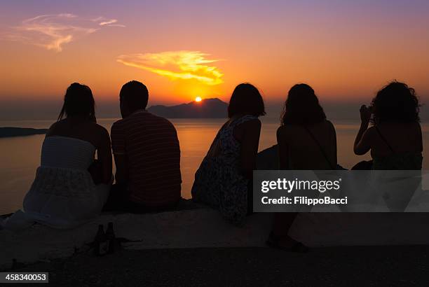 five friends admire sunset over the sea - milos stock pictures, royalty-free photos & images