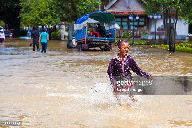 bambina corre attraverso floodwaters, siem reap, cambogia - monsoni foto e immagini stock