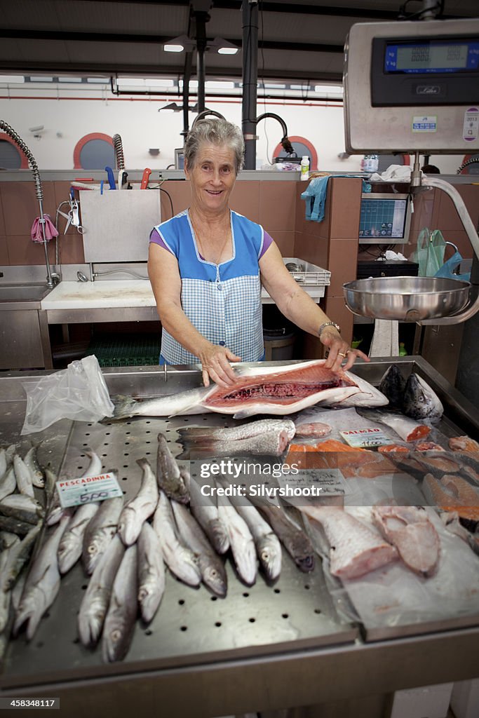 Femme montrant des poissons à la vente au marché.