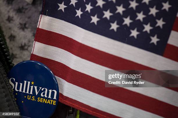 Supporter of Republican Senate candidate Dan Sullivan wears a button and an American flag during a rally at a PenAir airplane hangar on November 3,...