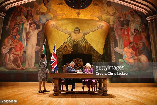 Prince Charles, Prince of Wales and Camilla, Duchess of Cornwall sign the visitor's book in front of a Diego Rivera mural at the launch of 'The Year...