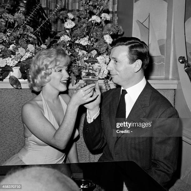 Actress Marilyn Monroe , and her co-star, French actor and singer Yves Montand share a glass of Champagne in 1960 in Hollywood after the screening of...