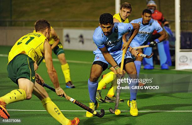 Glenn Simpson of Australia attacks the ball watched by India's Uthappa Sannuvanda during the first match of the four match field hockey Test series...