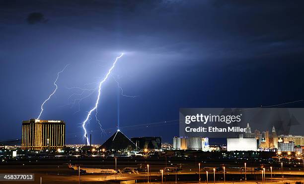Lightning flashes west of the Mandalay Bay Resort and Casino and the Luxor Hotel and Casino on the Las Vegas Strip as lights streak from an airplane...