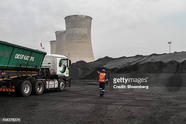 Worker supervises as a truck delivers coal supplies to the coal yard at the Grootvlei power station, operated by Eskom Holdings SOC Ltd., in...