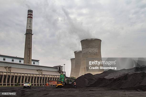 Worker supervises as a truck delivers coal supplies to the coal yard at the Grootvlei power station, operated by Eskom Holdings SOC Ltd., in...
