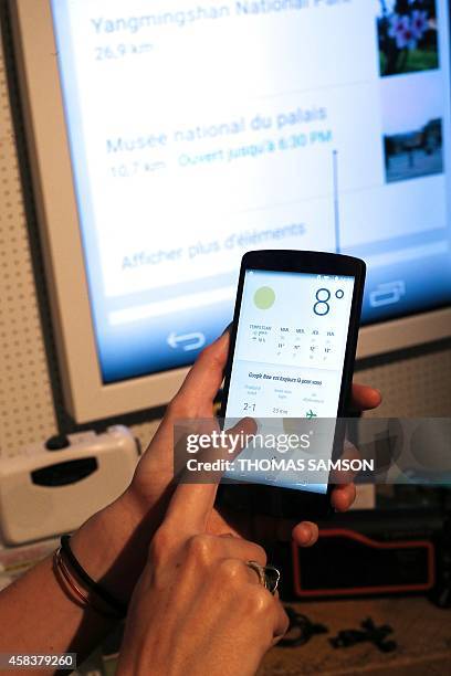 Woman uses a weather app on her smartphone during a Google promotion event at the City of Fashion and Design in Paris on November 4, 2014. AFP PHOTO...