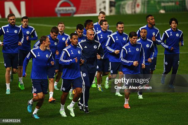 Players run during a FC Schalke 04 training session ahead of their UEFA Champions League Group G match against Sporting Club de Portugal at Estadio...