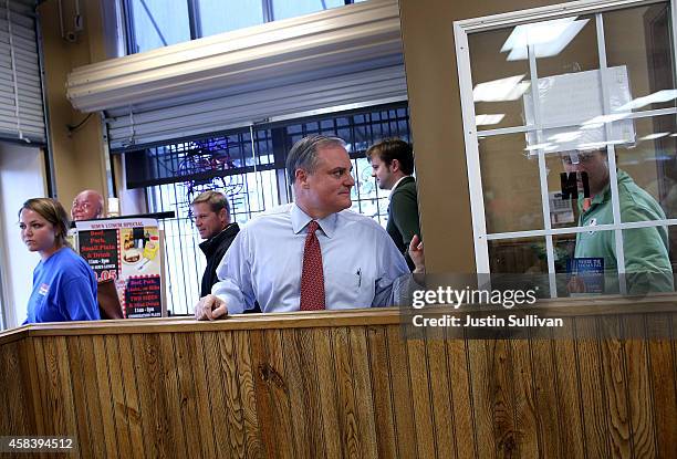 Sen. Mark Pryor holds a door open for members of his staff before greeting customers at Sim's BBQ on November 4, 2014 in Little Rock, Arkansas. As...