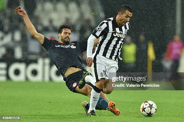 Carlos Tevez of Juventus is tackled by Alberto Botia of Olympiacos FC during the UEFA Champions League group A match between Juventus and Olympiacos...