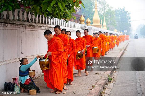 group of monks receiving food offering in street, laung prabang - theravada stock pictures, royalty-free photos & images