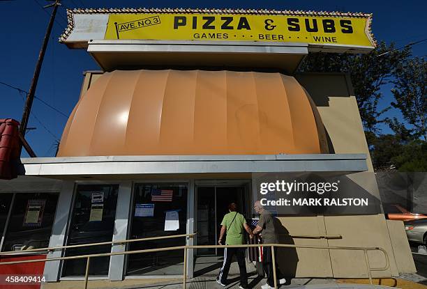 People arrive to vote at the Avenue 3 Pizza shop, used as a polling station during midterm elections in Long Beach, California on November 4, 2014....