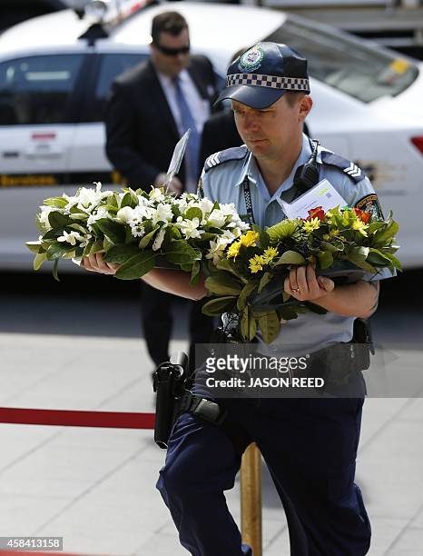 Policeman carries floral tributes into a state memorial service for former Australian prime minister Gough Whitlam at the Sydney Town Hall on...