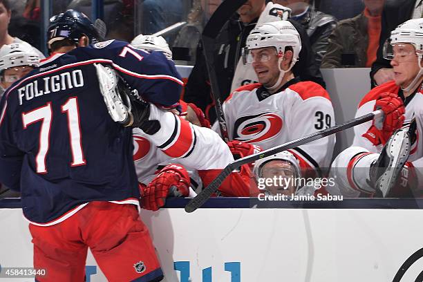 Nick Foligno of the Columbus Blue Jackets dumps Riley Nash of the Carolina Hurricanes back onto the bench with a check in the third period on...