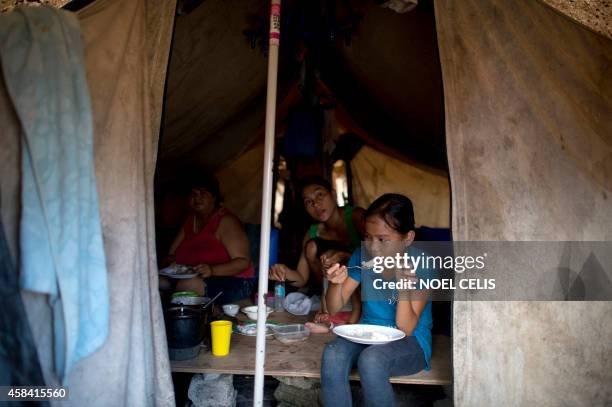 Philippines-typhoon,ADVANCER by Karl Malakunas This photo taken on October 16, 2014 shows a family eating their lunch inside a tent at a tent city...