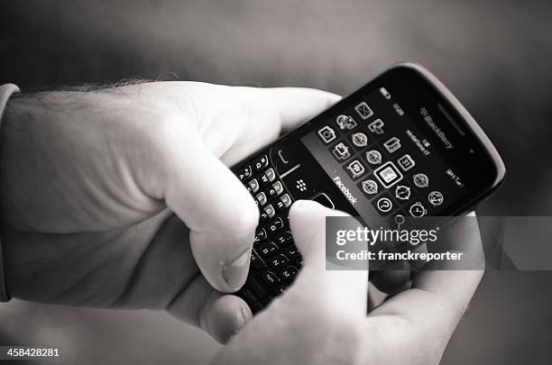 hand holding a blackberry smartphone with facebook.com apps - mobil brand name stock pictures, royalty-free photos & images