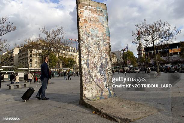 Man looks on November 5, 2014 at an original piece of the Berlin Wall displayed in Paris, 25 years after the Berlin Wall came tumbling down. AFP...