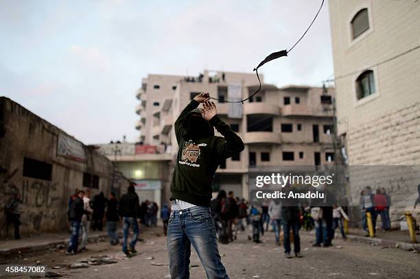 Palestinian protester fires a slingshot during the clashes with Israeli police at Shuafat refugee camp after a Palestinian rammed his vehicle into a...