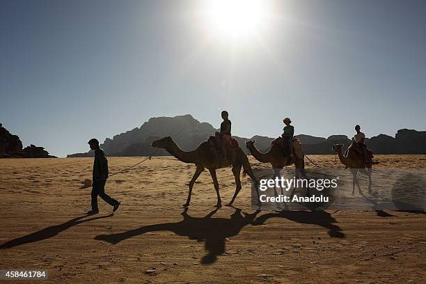 Tourists travel on camels through Wadi Araba in historical Petra city of southern Jordanian governorate Ma'an on October 20, 2014. Being among UNESCO...