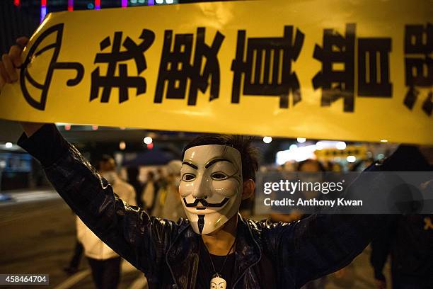 Pro-democracy protesters wear Guy Fawkes mask as they hold banners and shout slogans on a street near Hong Kong Government Complex in Admiralty...