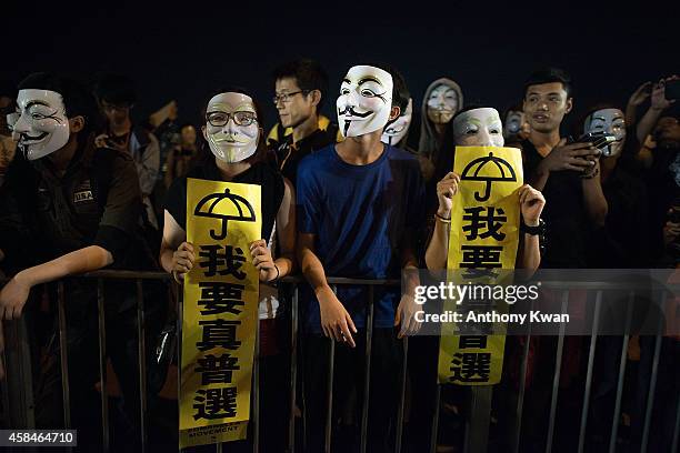 Pro-democracy protesters wear Guy Fawkes mask as they hold banners and shout slogans on a street near Hong Kong Government Complex in Admiralty...