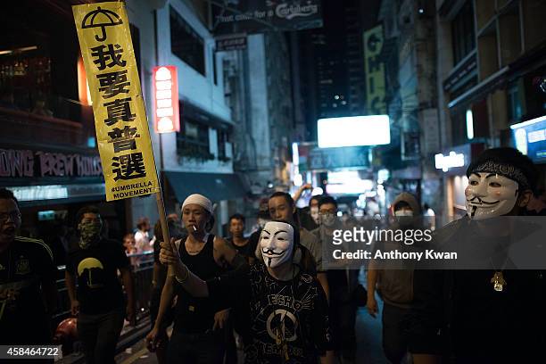 Pro-democracy protesters wear Guy Fawkes masks as they hold banners and shout slogans on a street near Hong Kong Government Complex in Admiralty...