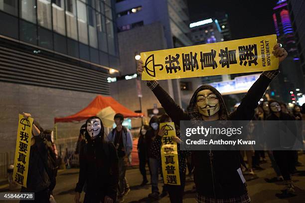 Pro-democracy protesters wear Guy Fawkes mask as they hold banners and shout slogans on a street near Hong Kong Government Complex in Admiralty...