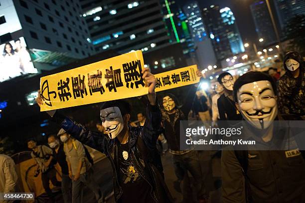 Pro-democracy protesters wear Guy Fawkes mask as they hold banners and shout slogans on a street near Hong Kong Government Complex in Admiralty...