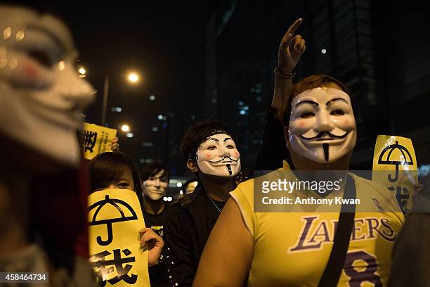 Pro-democracy protesters wear Guy Fawkes mask as they hold banners and shout slogans on a street near Hong Kong Government Complex in Admiralty...