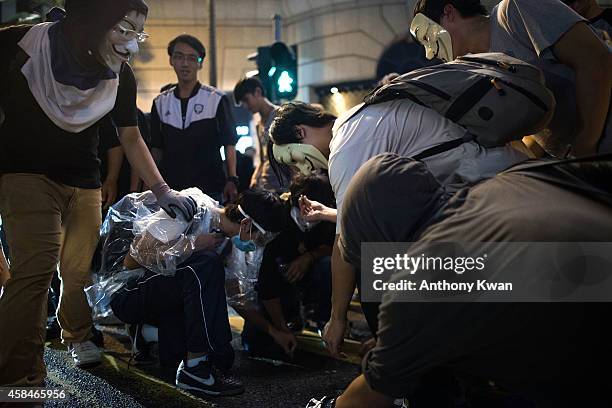 Pro-democracy protesters wear Guy Fawkes mask as they pick up coins on a street in Central district on November 6, 2014 in Hong Kong. Pro-democracy...