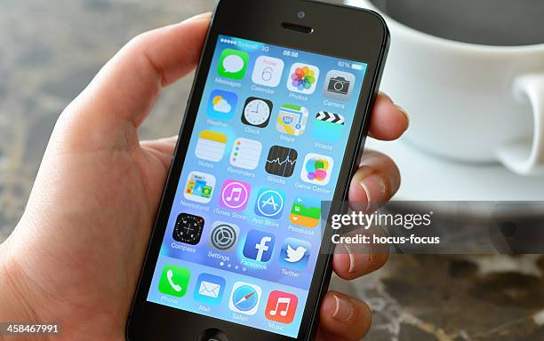 neue apple ios 7 betriebssystem auf iphone 5 - hand holding iphone stock-fotos und bilder