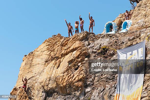 waving divers on the cliffs of acapulco - la quebrada acapulco stock pictures, royalty-free photos & images