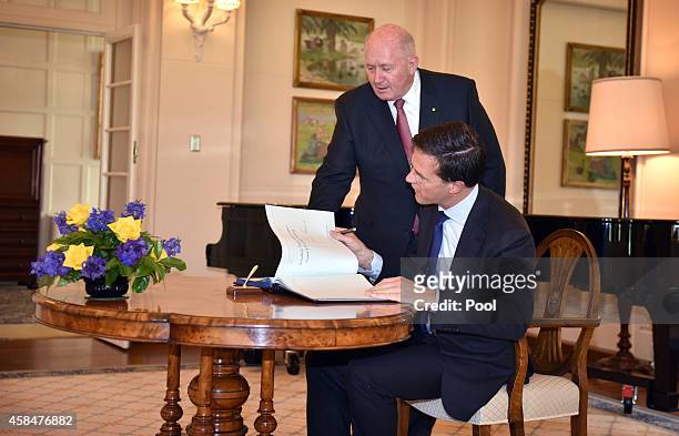 Australian Governor-General Peter Cosgrove assists as the Netherlands Prime Minister Mark Rutte signs the visitors book at Government House in on...